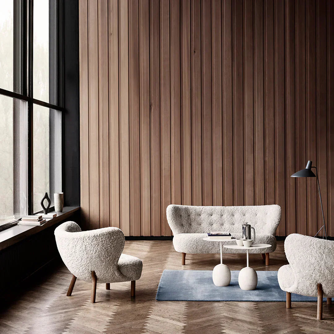 A cozy seating arrangement featuring the Little Petra sheepskin chair and sofa in a minimalist living room with soft natural lighting.