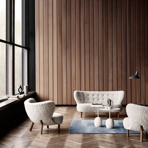 A cozy seating arrangement featuring the Little Petra sheepskin chair and sofa in a minimalist living room with soft natural lighting.