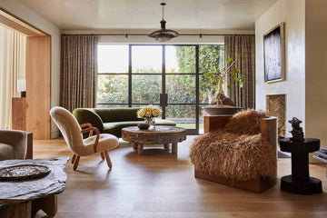 Serene living area with weathered armchair, raw-edge wood coffee table, and woven floor textures in a Wabi-Sabi interior" — reflects the use of imperfect, tactile materials and furnished simplicity.