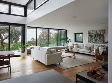 Minimalist living room with sleek white sofa, wood coffee table, and layered neutral-toned throws