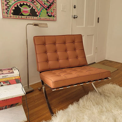 Brown leather chair in a room with books and a lamp.
