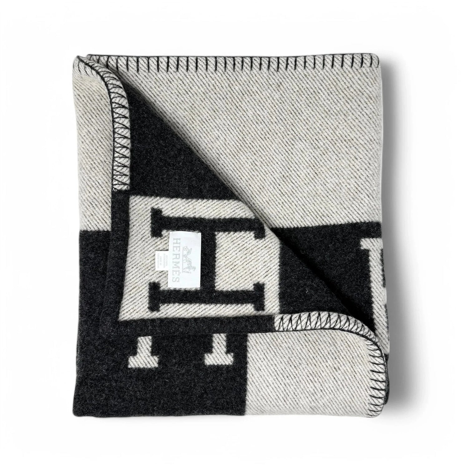 Folded gray and black patterned blanket with a brand logo on a white background