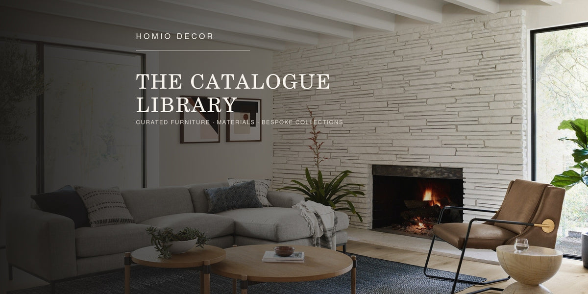 HOMIO DECOR catalogue library featuring a grey sectional sofa, leather lounge chair and solid wood tables in a refined interior.