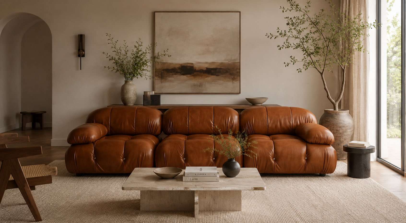 A warm brown leather sectional sofa in a styled living room setting with a beige coffee table, neutral walls, and large potted plants.