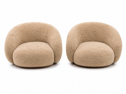 A pair of modern, rounded shearling armchairs in a warm beige/tan color, shown side-by-side against a plain white background.